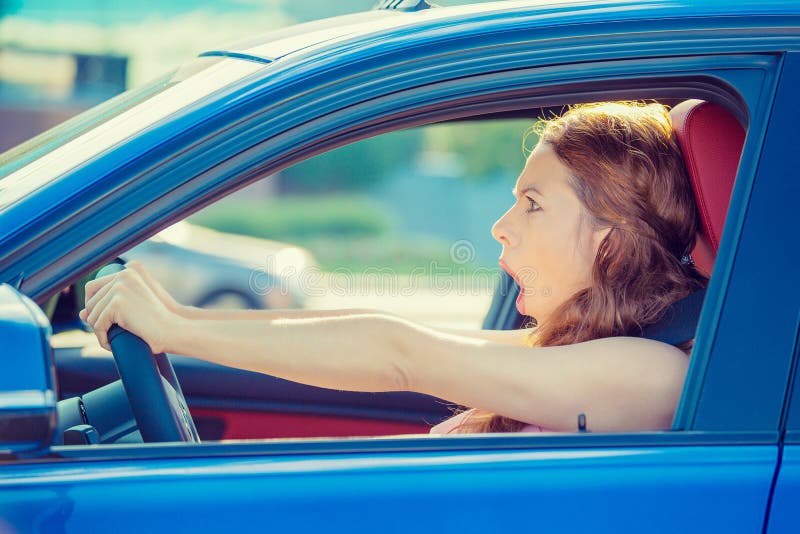 Dear in headlights. Fright face woman driving car wide open mouth eyes screaming squeezing wheel, side window view. Negative human face expression emotion reaction. Road trip risk danger concept