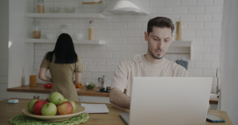 Frilansare som arbetar med en bärbar dator från hemmet när hon kokar mat i köket