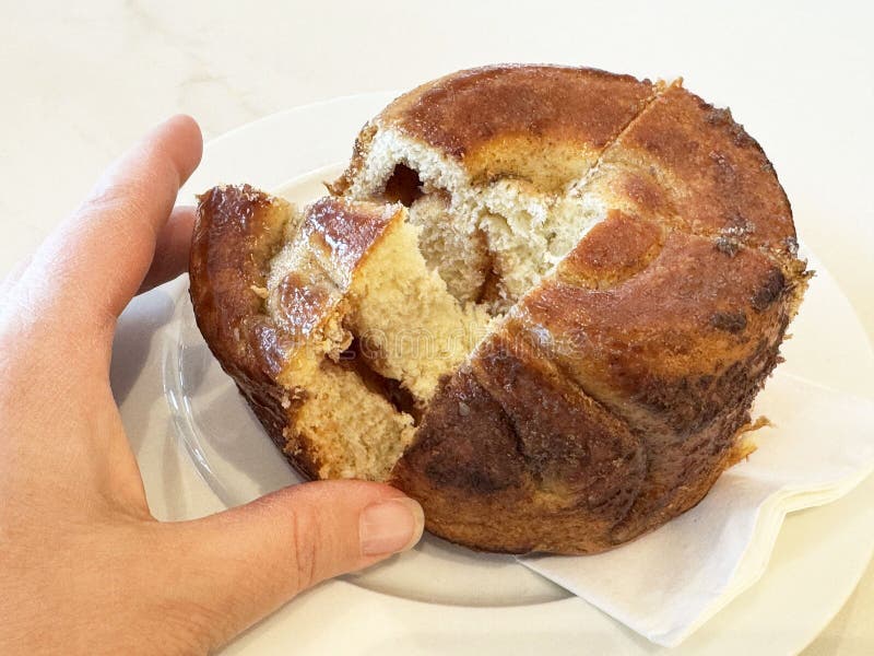 Frisch gebackene Zimtbrötchen mit Eiswürfelchen mit kaukasischer Hand lizenzfreie stockfotos