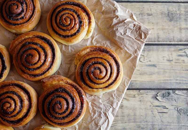 Frisch gebackene Zimtgebäckbrötchen mit Kakao und Gewürzen auf Pergamentpapier Nahaufnahme Beschneidungspfad eingeschlossen Kanel lizenzfreies stockbild