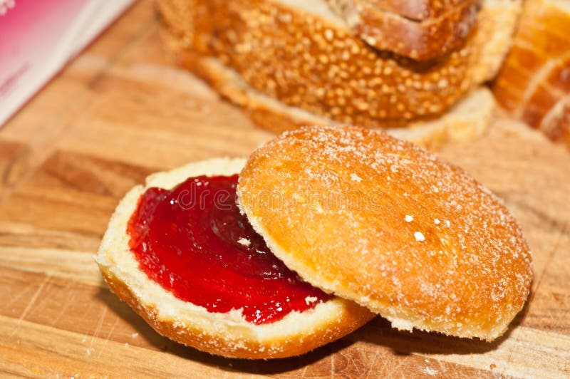 Frisch gebackener Geleedonut, schnitt offen, um rasberry Stau einzuspritzen lizenzfreies stockbild Frisch gebackener Geleedonut, schnitt offen, um rasberry Stau einzuspritzen lizenzfreies stockbild