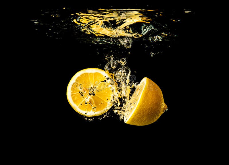 Frische gelbe Zitronenhalfen im Wasser spritzen auf schwarzem Hintergrund mit vielen Luftbläschen lizenzfreies stockfoto Frische gelbe Zitronenhalfen im Wasser spritzen auf schwarzem Hintergrund mit vielen Luftbläschen lizenzfreies stockfoto