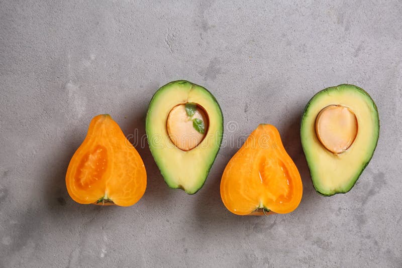 Frische geschnittene Avocado und Tomate auf grauem strukturiertem Hintergrund lizenzfreie stockfotos Frische geschnittene Avocado und Tomate auf grauem strukturiertem Hintergrund lizenzfreie stockfotos