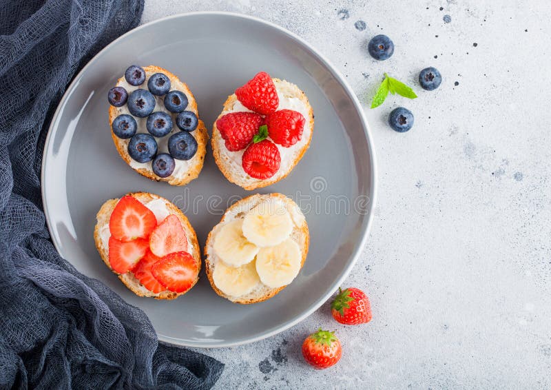 Frische gesunde Minisandwiche mit Sahne Käse, Früchte und Beeren in der grauen Platte mit Stoff Erdbeeren, Blaubeeren, Bananen a lizenzfreies stockfoto Frische gesunde Minisandwiche mit Sahne Käse, Früchte und Beeren in der grauen Platte mit Stoff Erdbeeren, Blaubeeren, Bananen a lizenzfreies stockfoto