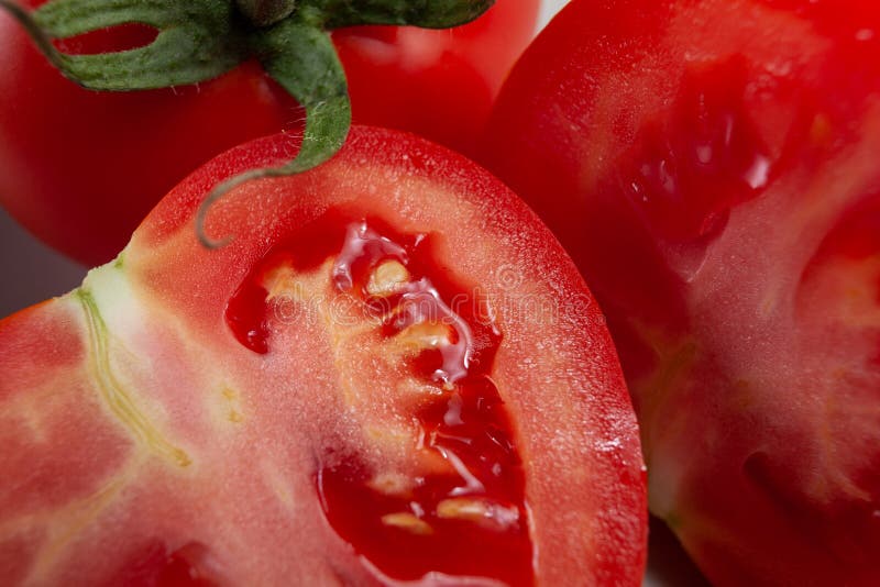 Frische, reife Tomate, Schnitt zur Hälfte, saftig, noch mit grünem Stamm lizenzfreies stockbild