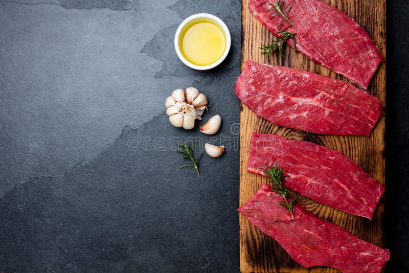 Frische Rindfleischsteaks des rohen Fleisches Rindsfilet auf hölzernem Brett, Gewürze, Kräuter, Öl auf Schiefergrauhintergrund Le stockbild Frische Rindfleischsteaks des rohen Fleisches Rindsfilet auf hölzernem Brett, Gewürze, Kräuter, Öl auf Schiefergrauhintergrund Le stockbild