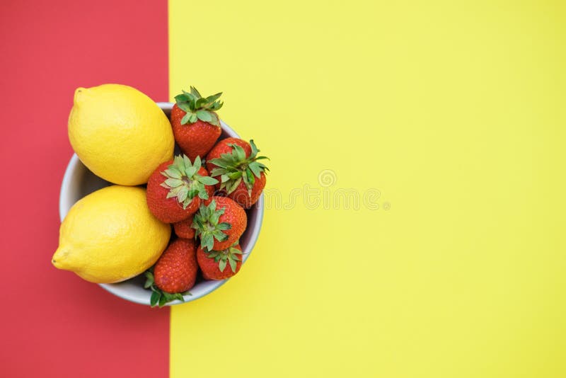 Frische Zitronen und Erdbeeren in einer Schüssel auf einer gelben und roten Rückseite stockfoto Frische Zitronen und Erdbeeren in einer Schüssel auf einer gelben und roten Rückseite stockfoto