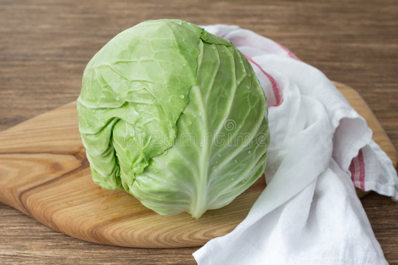 Frischer junger Kohl auf hölzernem Brett auf Holztisch stockbild Frischer junger Kohl auf hölzernem Brett auf Holztisch stockbild