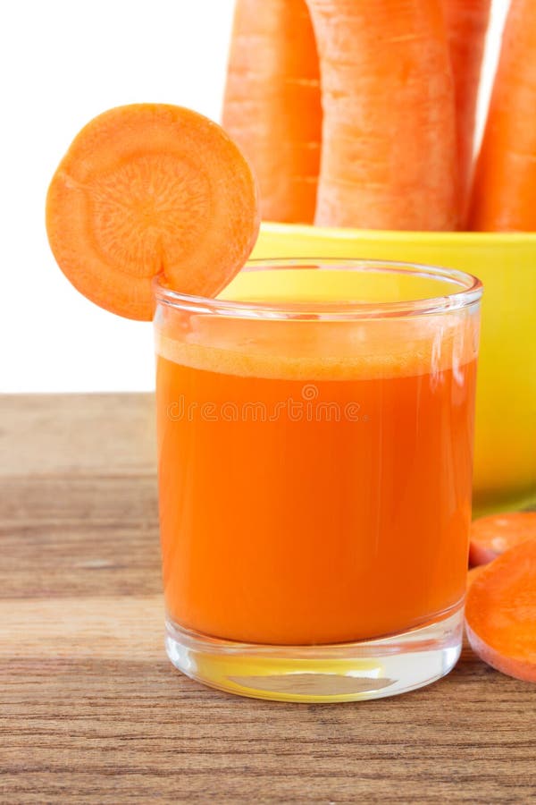 Frischer Karottensaft im Glas, in Scheiben und in Karotten Gemüse in der gelben Schüssel auf Holztisch, weißer Hintergrund lizenzfreie stockfotografie Frischer Karottensaft im Glas, in Scheiben und in Karotten Gemüse in der gelben Schüssel auf Holztisch, weißer Hintergrund lizenzfreie stockfotografie