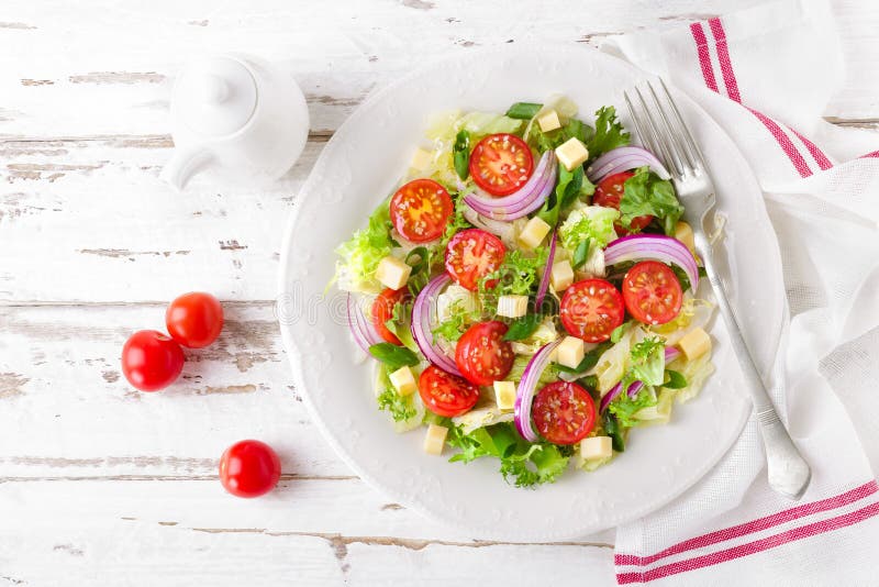 Frischgemüsesalat mit Tomaten, Kopfsalat, Zwiebel und Käse auf weißem hölzernem Hintergrund Gesunde vegetarische Nahrung lizenzfreie stockfotos Frischgemüsesalat mit Tomaten, Kopfsalat, Zwiebel und Käse auf weißem hölzernem Hintergrund Gesunde vegetarische Nahrung lizenzfreie stockfotos