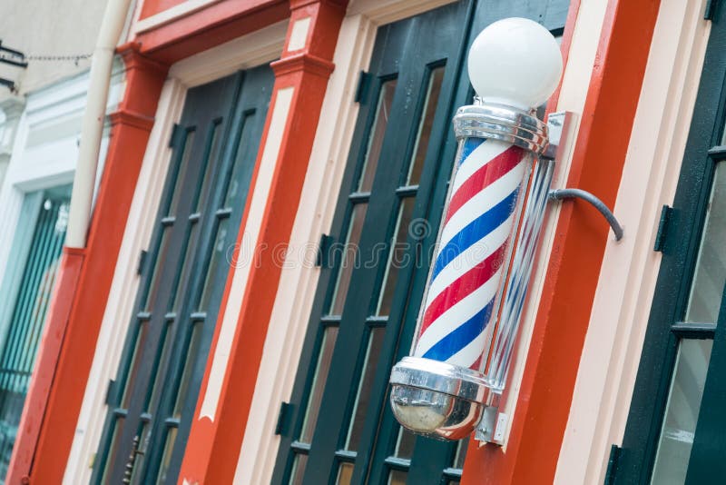 Old Fashioned Barbershop Pole On Store Front in Town. Old Fashioned Barbershop Pole On Store Front in Town