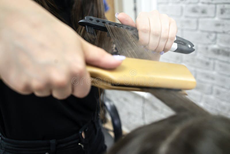 Friseur macht Haarlaminierung in einem Schönheitssalon für ein Mädchen mit dem brunette Haar stockfotografie Friseur macht Haarlaminierung in einem Schönheitssalon für ein Mädchen mit dem brunette Haar stockfotografie