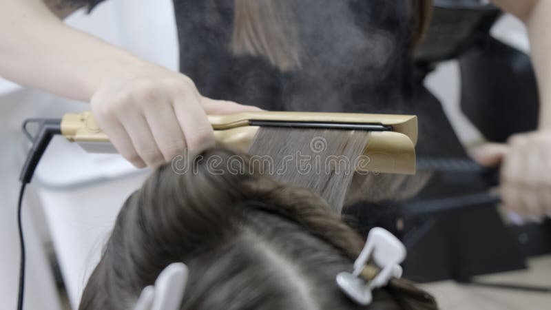 Friseur macht Haarlaminierung in einem Schönheitssalon für ein Mädchen mit dem brunette Haar Abschluss oben lizenzfreie stockfotos Friseur macht Haarlaminierung in einem Schönheitssalon für ein Mädchen mit dem brunette Haar Abschluss oben lizenzfreie stockfotos