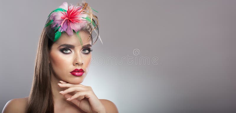 Frisyr och smink - härlig äkta naturlig brunett med kulöra blommor i hennes långa hår. Konststående royaltyfri foto Frisyr och smink - härlig äkta naturlig brunett med kulöra blommor i hennes långa hår. Konststående royaltyfri foto