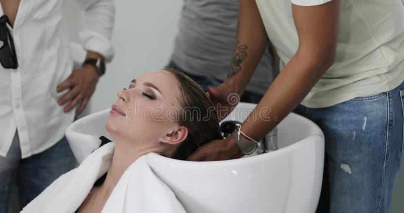 Frisörstylisten tvättar hår för kvinna` s i skönhetstudion