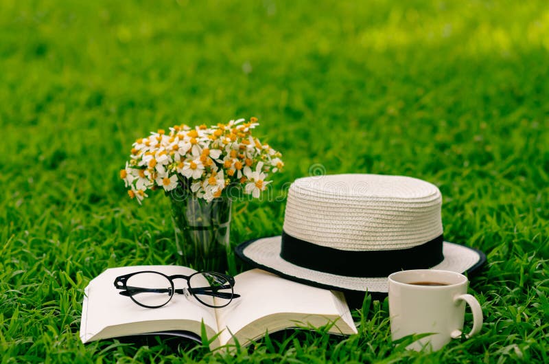Leisure in morning at garden with coffee, book , hat and flowers on the lawn. Leisure in morning at garden with coffee, book , hat and flowers on the lawn