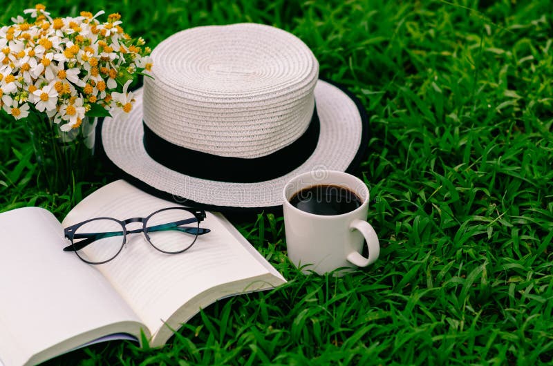 Leisure in morning at garden with coffee, book , hat and flowers on the lawn. Leisure in morning at garden with coffee, book , hat and flowers on the lawn.