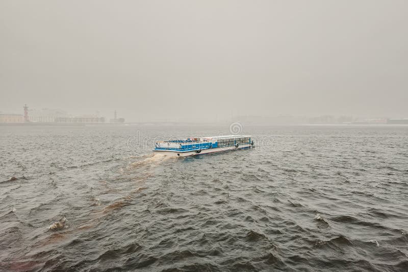 Pleasure boat on the Neva river in a spring snowstorm. St. Petersburg. Russia. Early spring navigation on the river in very bad weather, the beginning of the tourist season in St. Petersburg. Pleasure boat on the Neva river in a spring snowstorm. St. Petersburg. Russia. Early spring navigation on the river in very bad weather, the beginning of the tourist season in St. Petersburg