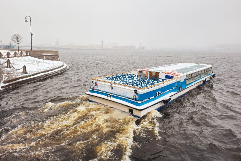 Pleasure boat on the Neva river in a spring snowstorm. St. Petersburg. Russia. Early spring navigation on the river in very bad weather, the beginning of the tourist season in St. Petersburg. Pleasure boat on the Neva river in a spring snowstorm. St. Petersburg. Russia. Early spring navigation on the river in very bad weather, the beginning of the tourist season in St. Petersburg