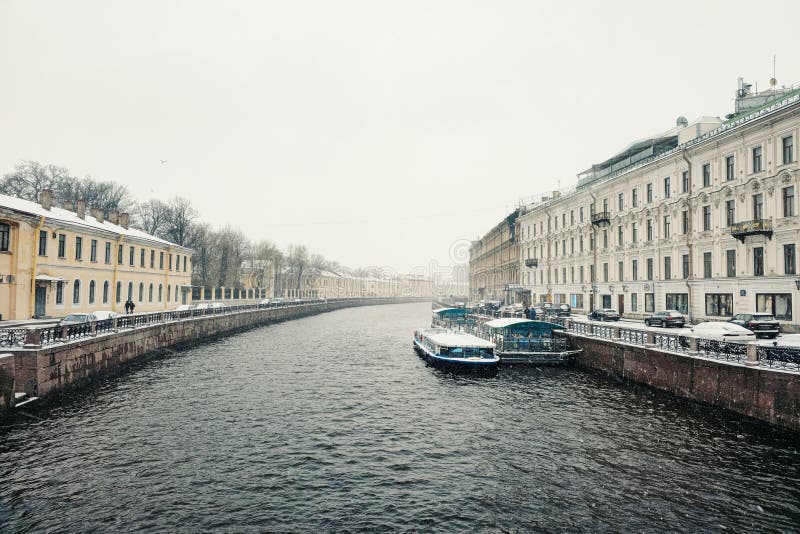 A pleasure boat is moored on the river in a spring snowstorm. Saint-Petersburg. Russia. Early spring navigation on the river in very bad weather, the beginning of the tourist season in St. Petersburg. A pleasure boat is moored on the river in a spring snowstorm. Saint-Petersburg. Russia. Early spring navigation on the river in very bad weather, the beginning of the tourist season in St. Petersburg