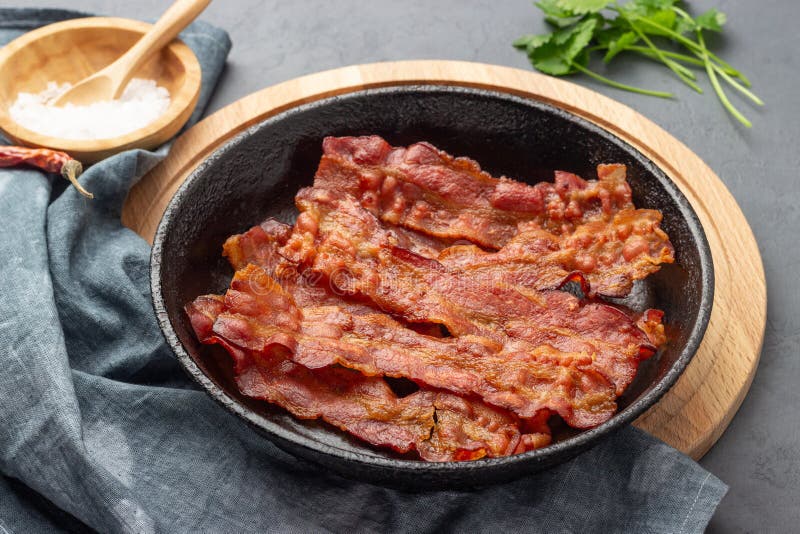 Frittierter Speck in einer gusseisernen Pfanne lizenzfreie stockbilder