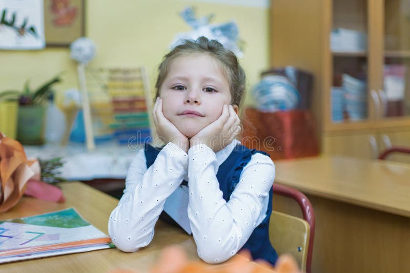 A frivolous schoolgirl of primary classes sits at a desk