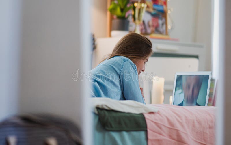 Frohe junges Mädchen mit Laptop auf on-line-Datierungskonzept des Betts. stockbilder