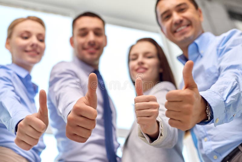 Frohe lächelnder Geschäftsteam, das sich Daumen zeigt stockfotos