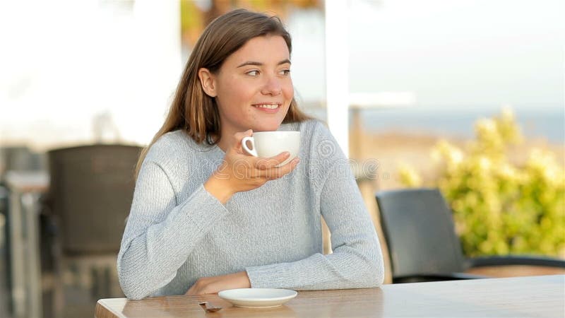 Frohe Mädchen, das in einem Coffee-Shop in Zeitlupe trinkt