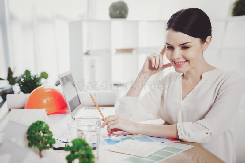 Frohe positive Frau, die im Büro arbeitet stockbild