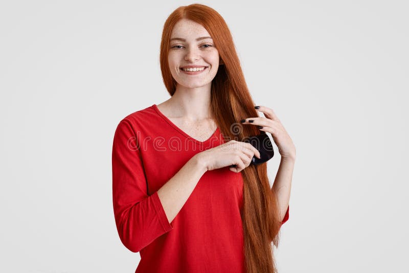 Frohe redhaired Frau mit reizend Lächeln, kämmt ihr foxy Haar, lässt sommersprossiges Gesicht, kleiden in der roten Strickjacke, lizenzfreie stockbilder Frohe redhaired Frau mit reizend Lächeln, kämmt ihr foxy Haar, lässt sommersprossiges Gesicht, kleiden in der roten Strickjacke, lizenzfreie stockbilder