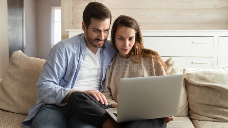 Frohe tausendjähriges verheiratetes Paar, das zu Hause Computerbildschirm betrachtet. lizenzfreie stockfotos
