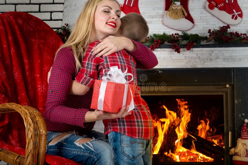 Frohe Weihnachten und frohe Feiertage! Netter Sohn gibt seiner geliebten Mutter ein Geschenk Neues Jahr ` s Innenraum im Wohnzimm lizenzfreie stockbilder Frohe Weihnachten und frohe Feiertage! Netter Sohn gibt seiner geliebten Mutter ein Geschenk Neues Jahr ` s Innenraum im Wohnzimm lizenzfreie stockbilder