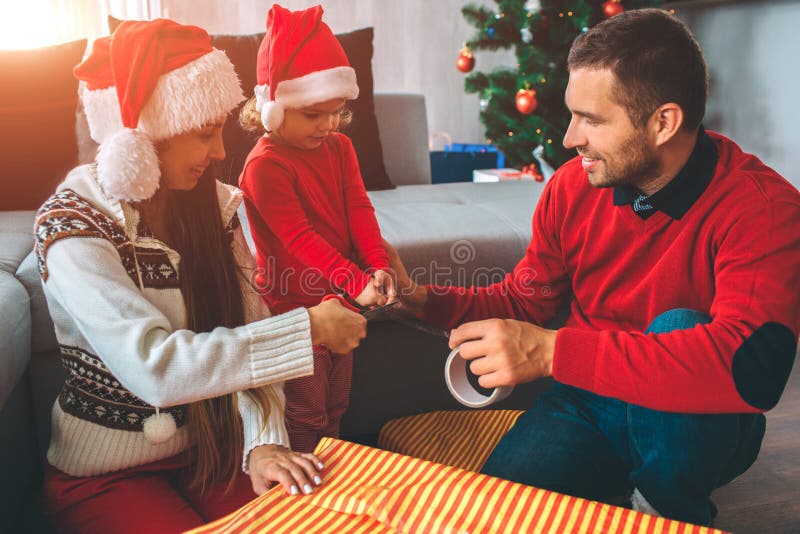 Frohe Weihnachten und guten Rutsch ins Neue Jahr Nettes Bild der Familie Geschenke zusammen vorbereitend Griffband des Mädchens u lizenzfreie stockfotografie Frohe Weihnachten und guten Rutsch ins Neue Jahr Nettes Bild der Familie Geschenke zusammen vorbereitend Griffband des Mädchens u lizenzfreie stockfotografie