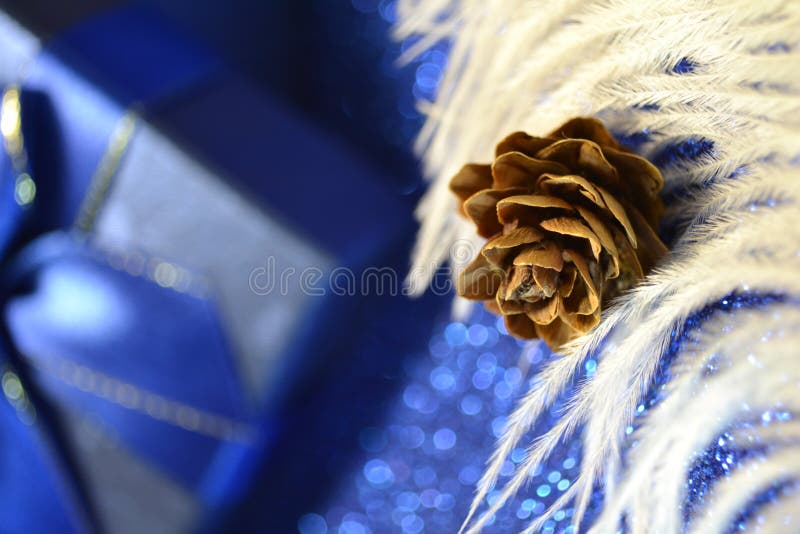 Frohe Weihnachtsblauer Geschenkkasten mit Bänderbogen auf dem Hintergrund mit weißer Feder und Kegel lizenzfreies stockfoto Frohe Weihnachtsblauer Geschenkkasten mit Bänderbogen auf dem Hintergrund mit weißer Feder und Kegel lizenzfreies stockfoto