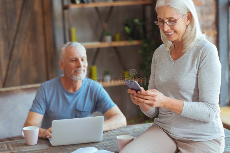 Frohe ältere Frau, die ihr intelligentes Telefon verwendet stockfotografie Frohe ältere Frau, die ihr intelligentes Telefon verwendet stockfotografie