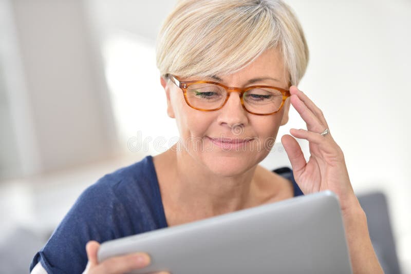 Frohe ältere Frau, die Tablette verwendet stockfoto Frohe ältere Frau, die Tablette verwendet stockfoto
