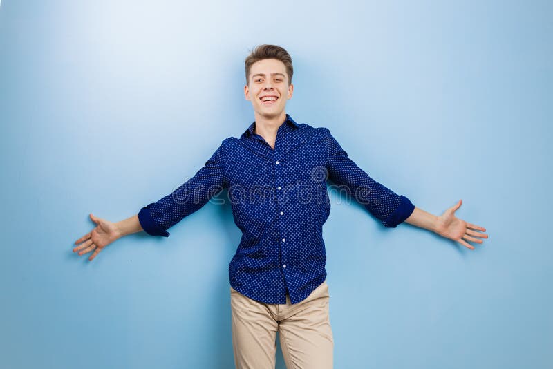 Froher aufgeregter junger dunkelhaariger Kerl, der Kamera mit glücklichem Ausdruck betrachtet und die Arme, stehend über Blau anh stockfotos Froher aufgeregter junger dunkelhaariger Kerl, der Kamera mit glücklichem Ausdruck betrachtet und die Arme, stehend über Blau anh stockfotos