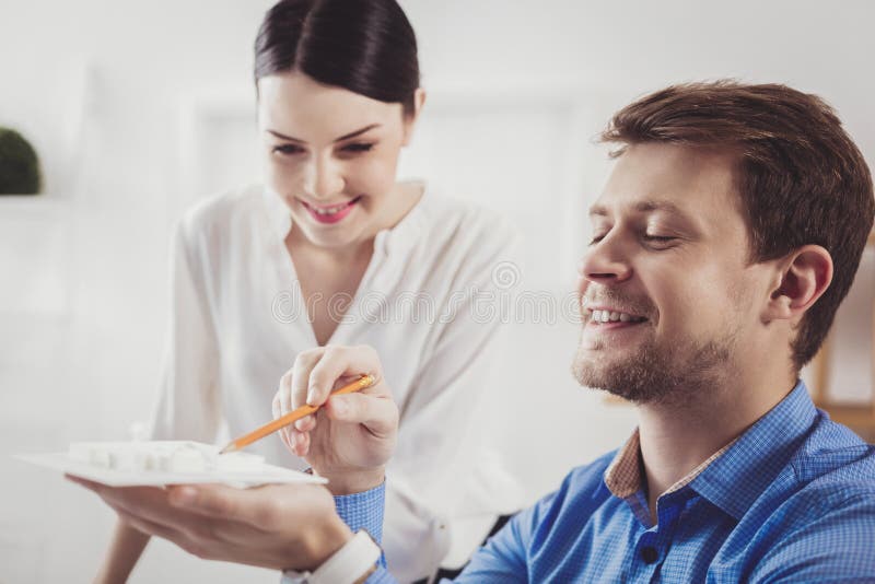 Froher netter Mann, der ein Hausmodell hält stockfotografie