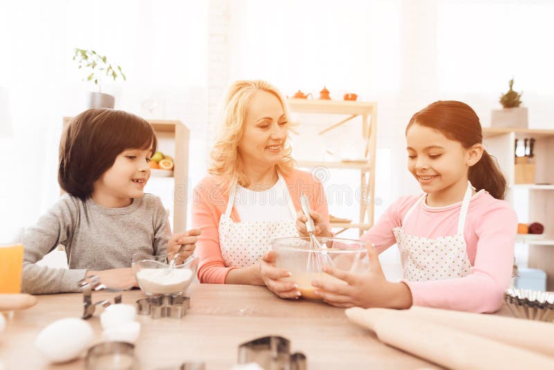 Frohes kleines Mädchen schlägt Eier in der Schüssel mit Milch und ihr Bruder gießt Mehl lizenzfreie stockbilder Frohes kleines Mädchen schlägt Eier in der Schüssel mit Milch und ihr Bruder gießt Mehl lizenzfreie stockbilder