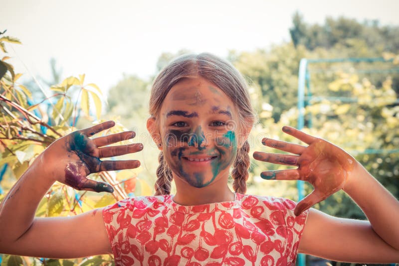 Frohes lächelndes gemaltes Gesicht des kreativen Kindermädchen-Malers, das Händen helle Sommertageskonzeptkinderkunstentwicklung stockfotos Frohes lächelndes gemaltes Gesicht des kreativen Kindermädchen-Malers, das Händen helle Sommertageskonzeptkinderkunstentwicklung stockfotos