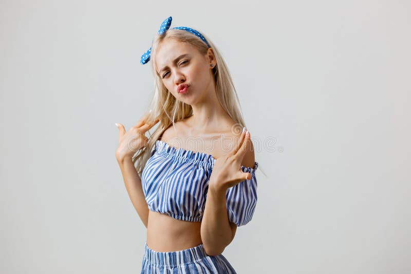 Frohes und aufgeregtes schönes blondes Mädchen in der Sommerausstattung, werfend an der Kamera auf, welche die Fingergewehrgeste lizenzfreies stockfoto Frohes und aufgeregtes schönes blondes Mädchen in der Sommerausstattung, werfend an der Kamera auf, welche die Fingergewehrgeste lizenzfreies stockfoto