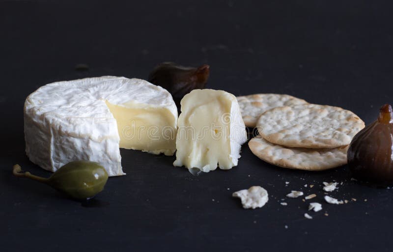 Fromage de camembert, figues, baie de câpre et biscuits sur le backgr noir photographie stock Fromage de camembert, figues, baie de câpre et biscuits sur le backgr noir photographie stock