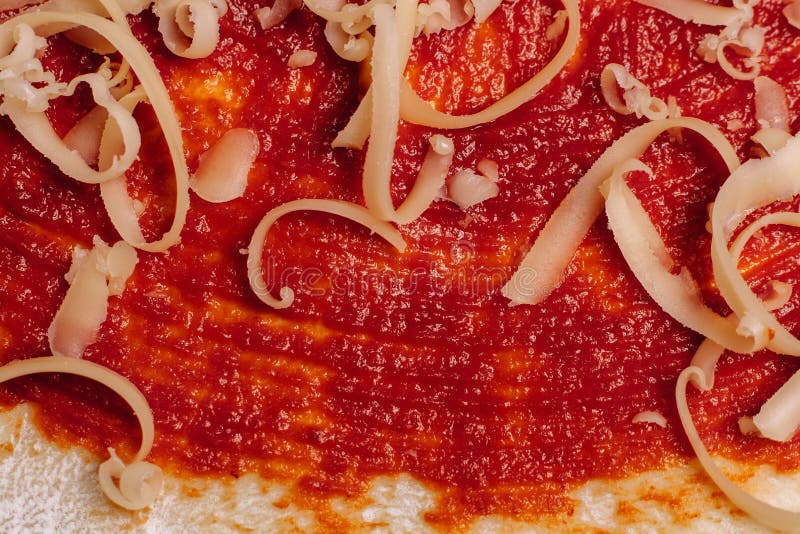 Fromage râpé pour la fin de pizza sur la pâte enduite de ketchup photos stock Fromage râpé pour la fin de pizza sur la pâte enduite de ketchup photos stock