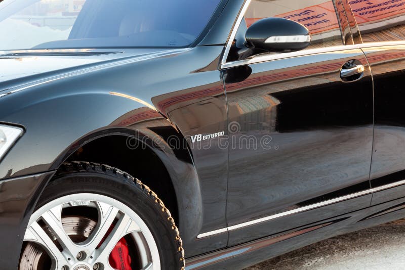 The front of the fender of a black car with wheels and a side rear-view mirror of a representative business class of the Mercedes-