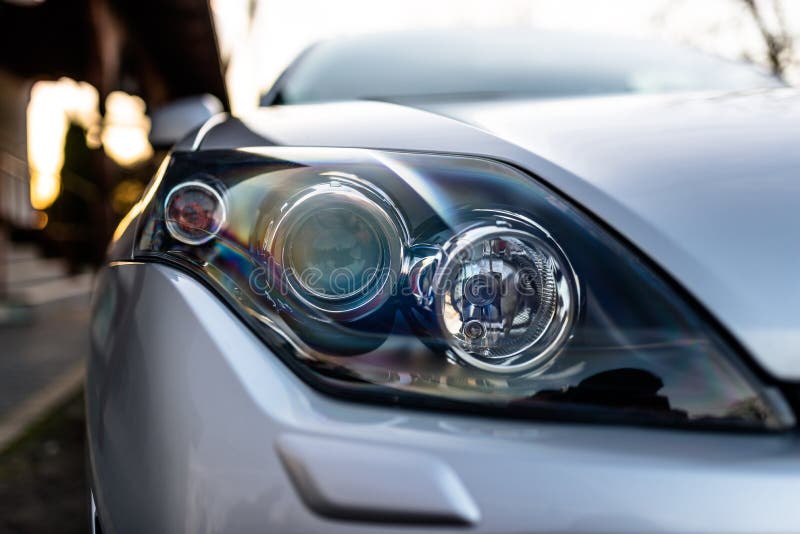 Front Headlight of a Silver, Modern Car with Three Lamps in the Middle