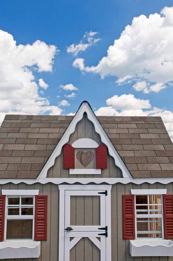 Closeup view of the front and door to a small house or little cottage with window boxes and red shutters. Closeup view of the front and door to a small house or little cottage with window boxes and red shutters.