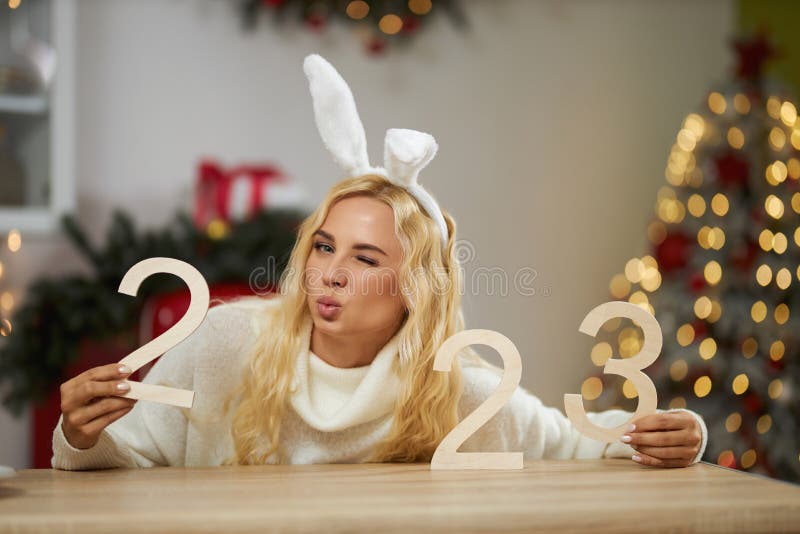 Beautiful, seductive woman having photoshoot at studio decorated with christmas tree.