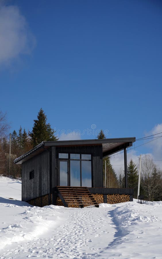 Front View of Black Modern Wooden Cabin on Snowy Mountains Stock Image