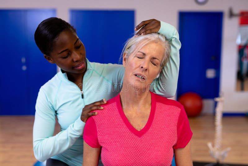 Female Physiotherapist Giving Neck Massage To Active Senior Woman In Sports Center Stock Image